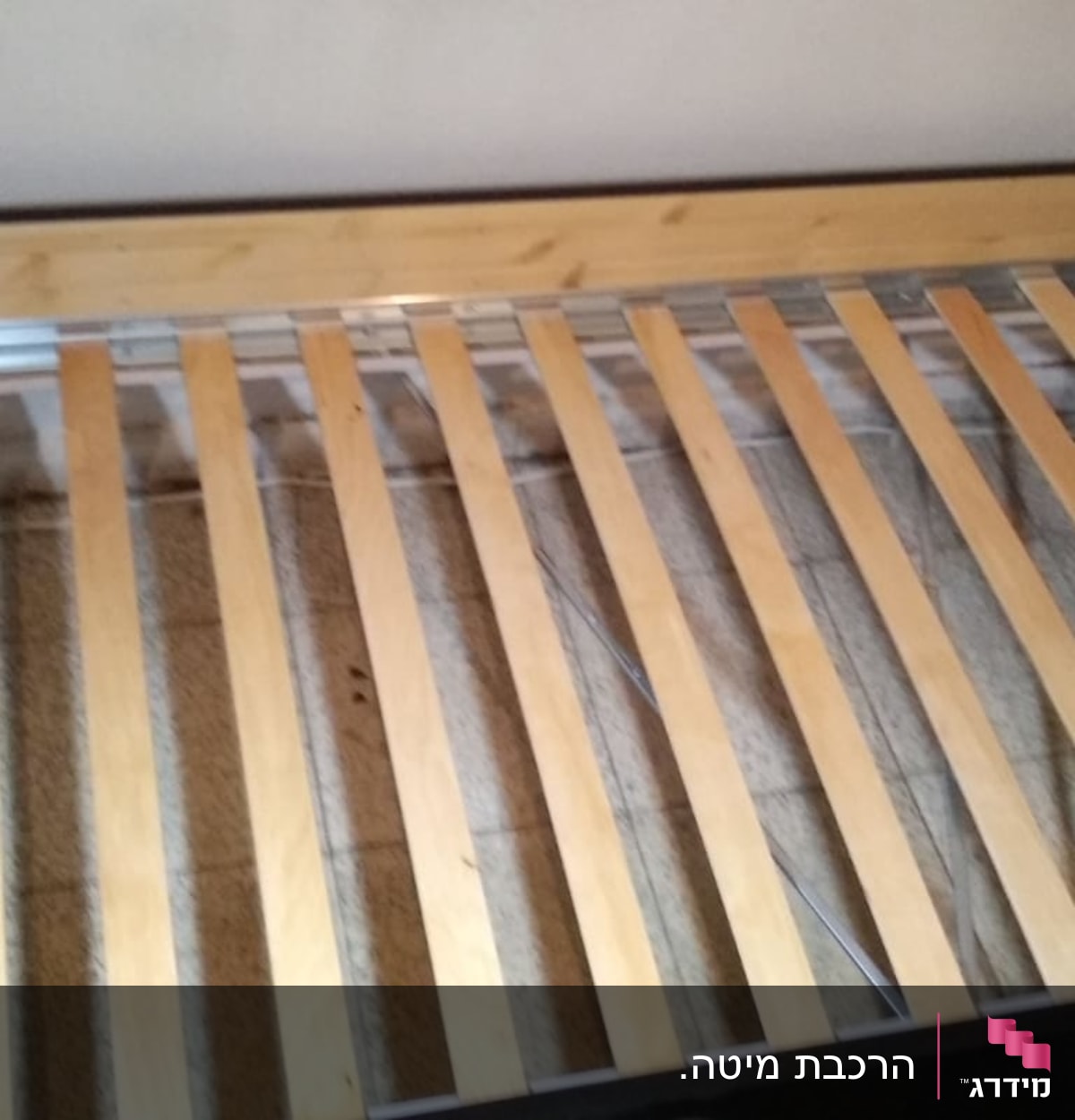 מסגרת מיטה עם קרשים מעץ, אדם עובד בצד